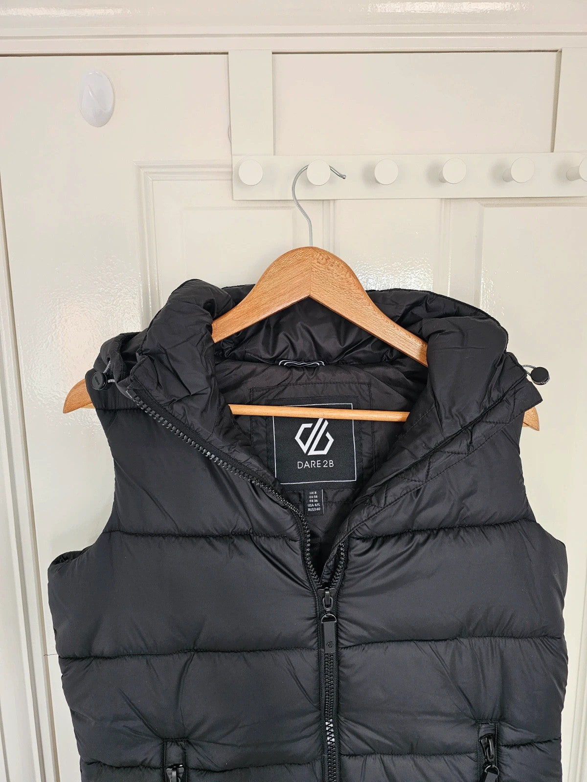Dare2b black longline hooded puffer gilet with zipper, waterproof material, sleeveless design.