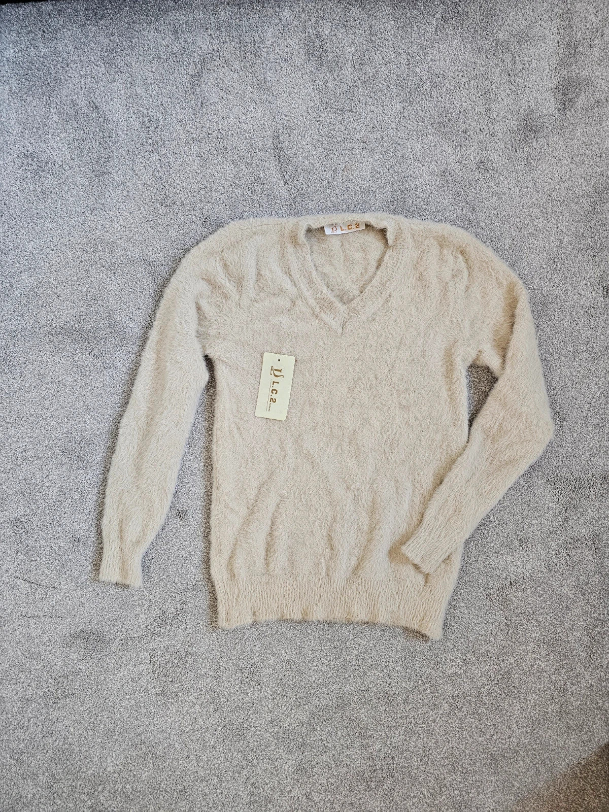 Generic cream fluffy knitted V-neck jumper with long sleeves and soft texture.