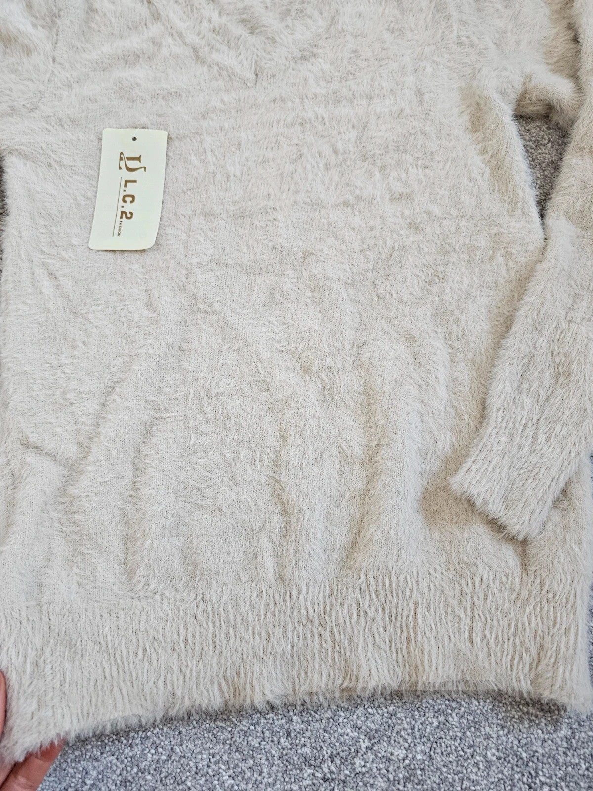 Generic cream fluffy knitted V-neck jumper with long sleeves and soft texture.