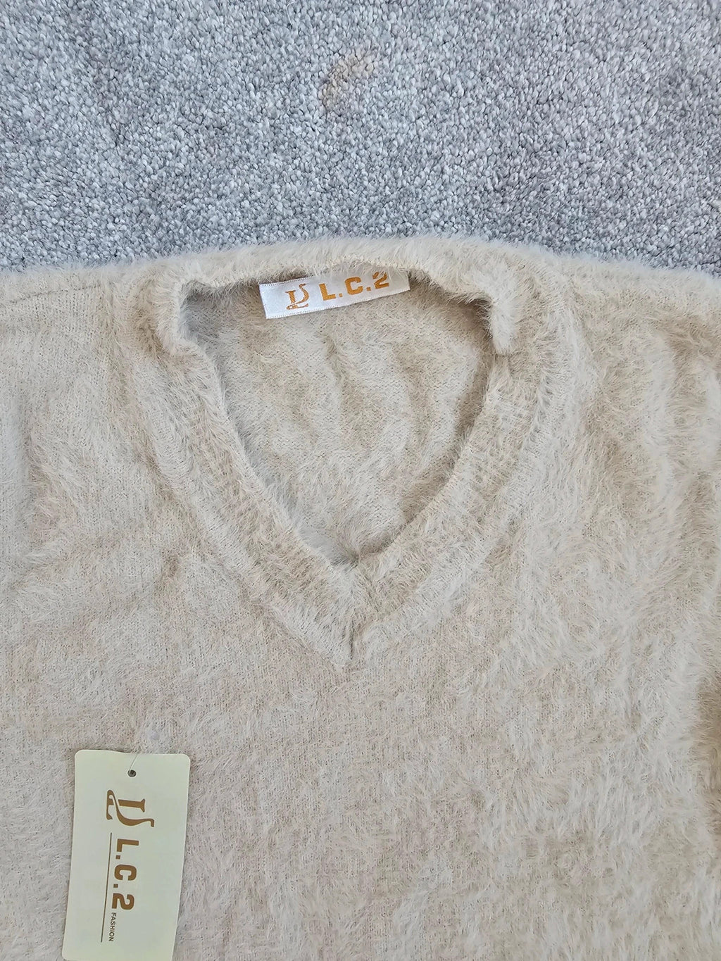 Generic cream fluffy knitted V-neck jumper with long sleeves and soft texture.