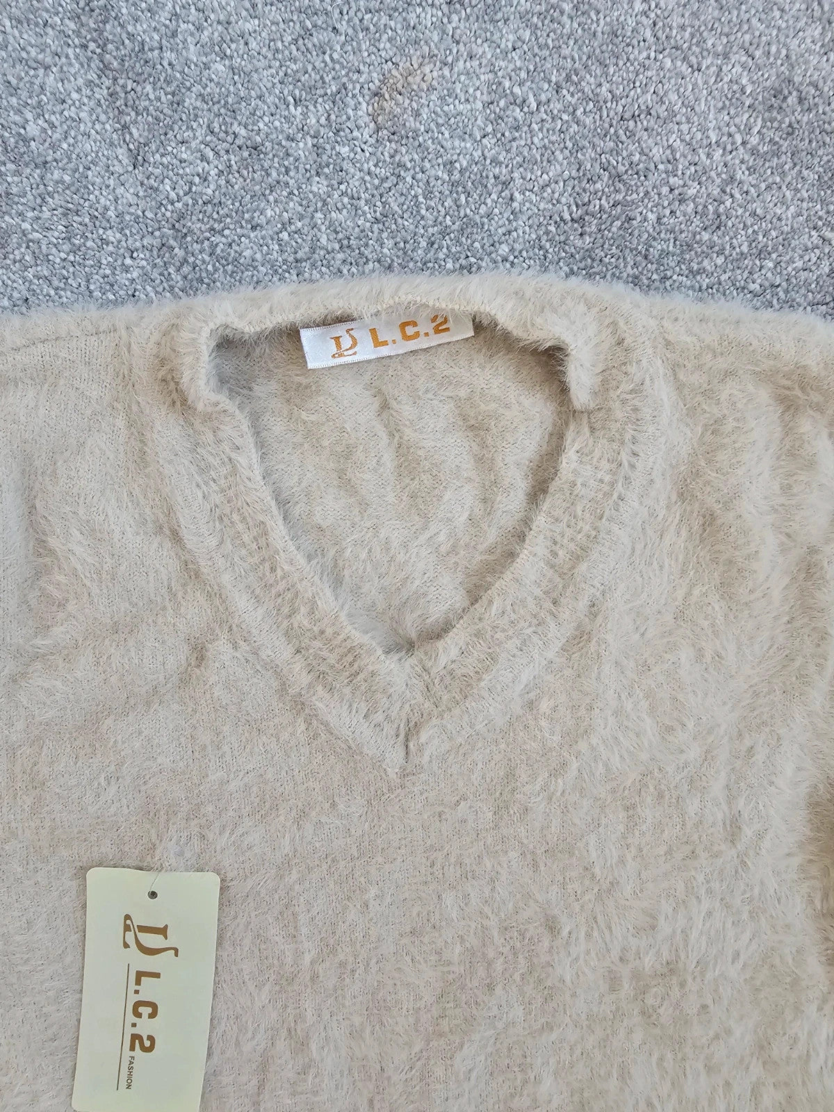 Generic cream fluffy knitted V-neck jumper with long sleeves and soft texture.