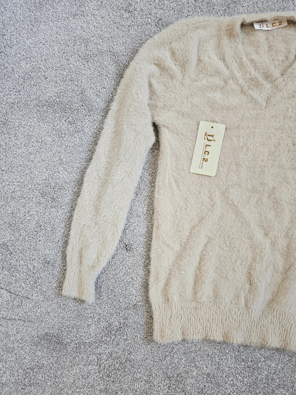 Generic cream fluffy knitted V-neck jumper with long sleeves and soft texture.
