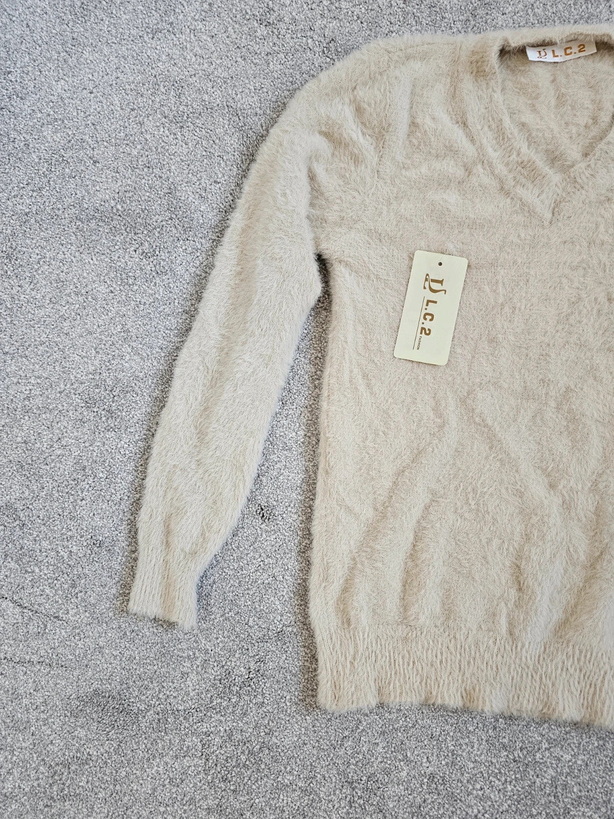 Generic cream fluffy knitted V-neck jumper with long sleeves and soft texture.